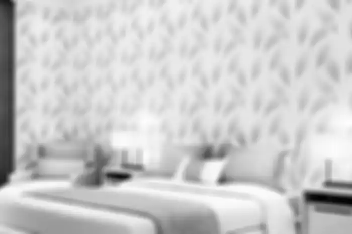 Ilustrasi pengaplikasian wallpaper dinding kamar tidur motif daun. 