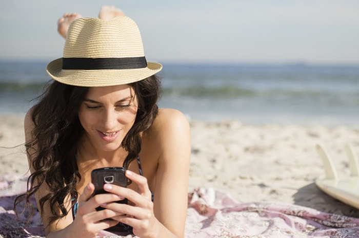 USA, New York State, Rockaway Beach, Woman using cell phone on beach