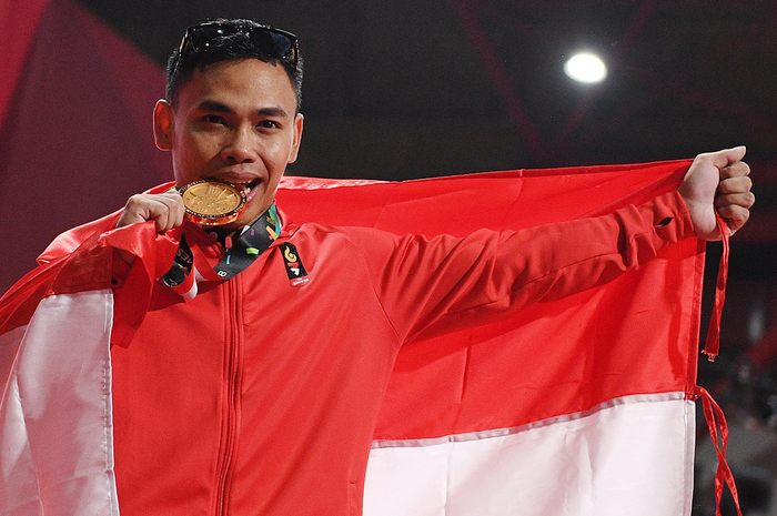 Lifter Indonesia Eko Yuli menggigit medali emasnya usai menjuarai angkat besi putra grup A nomor 62 