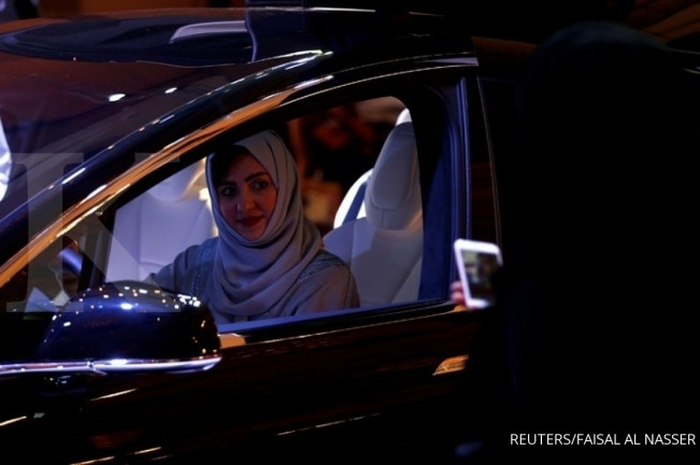 A Saudi woman is photographed as she checks a car at a showroom in Riyadh, Saudi Arabia October 5