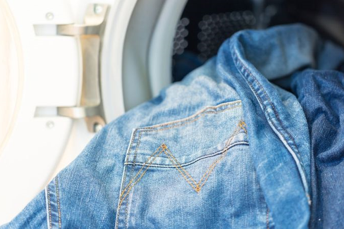 Ilustrasi Jeans dimasukan ke dalam mesin cuci.