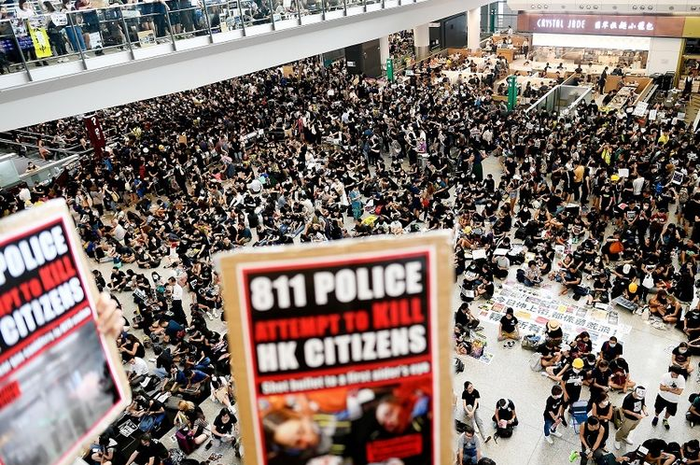 Massa pengunjuk rasa memadati aula kedatangan di Bandara Internasional Hong Kong, Senin (12/8/2019). Pengunjuk rasa yang mencapai lebih dari 5.000 orang memaksa dihentikannya operasional bandara.