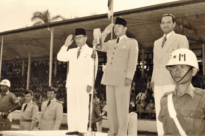 Presiden Soekarno (tengah) dan Wakil Presiden Mohammad Hatta (kiri) membuka Pekan Olahraga Angkatan Perang di Stadion Ikada Jakarta, September 1952. Hadir di panggung kehormatan Menteri Pertahanan Hamengku Buwono IX (kanan).
