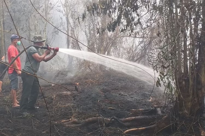 Petugas TNI dan warga memadamkan api karhutla yang mendekati rumah warga di Desa Rimbi Panjang, Kecamatan Tambang, Kabupaten Kampar, Riau, Selasa (17/9/2019)