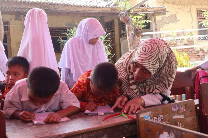 Seorang guru membimbing siswa di SD Negeri Malangsari II, Kecamatan Pedes, Karawang, Jawa Barat, Rabu (16/10/2019). Mereka belajar di kelas darurat.