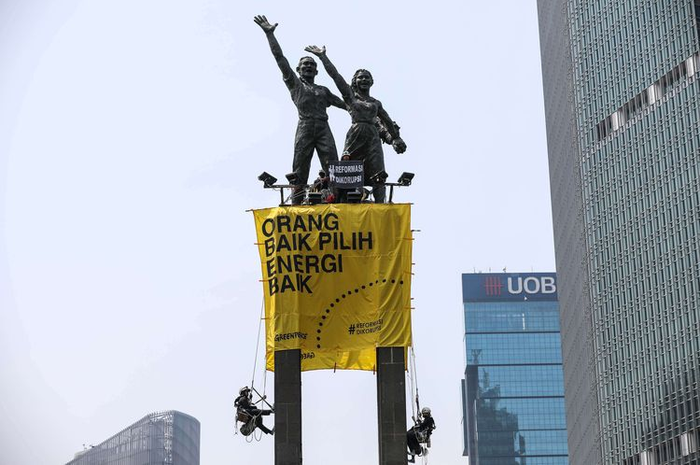 Aktivis Greenpeace memasang spanduk di patung Bundaran HI
