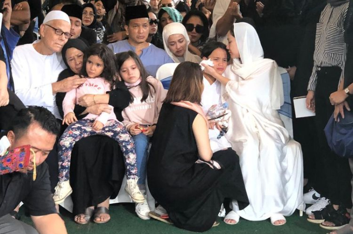 Penyanyi Bunga Citra Lestari (bergaun dan berkerudung putih) mencium kening putranya, Noah Sinclair, pada pemakaman suaminya, Ashraf Sinclair, di San Diego Hills, Karawang, Jawa Barat, Selasa (18/2/2020).(KOMPAS.com/REVI C RANTUNG)