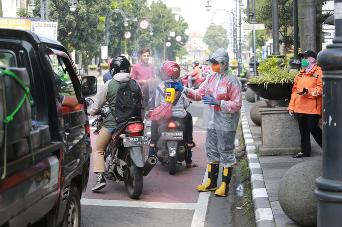  Srikandi Damkar Bandung sedang menyemprotkan cairan disinfektan kepada para pengendara kendaraan bermotor di Jalan Asia Afrika, Kota Bandung