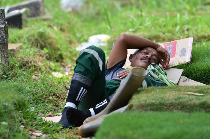 Foto yang diambil pada 6 Mei 2020, memperlihatkan Minar salah seorang penggali makam di pemakaman Pondok Ranggon, Jakarta Timur, sedang beristirahat. Pondok Ranggon merupakan salah satu dari dua pemakaman yang ditunjuk khusus untuk mengubur korban meninggal Covid-19 di Jakarta. AFP memberitakan para penggali makam bekerja 15 jam per hari, 7 hari per minggu, dengan gaji bulanan Rp 4,2 juta. 