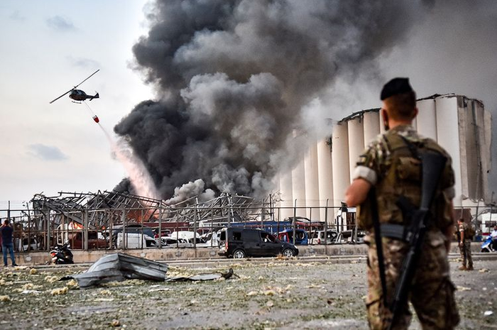 Petugas berjaga saat helikopter memadamkan api di lokasi ledakan di Beirut, Lebanon Selasa (4/8/2020) 