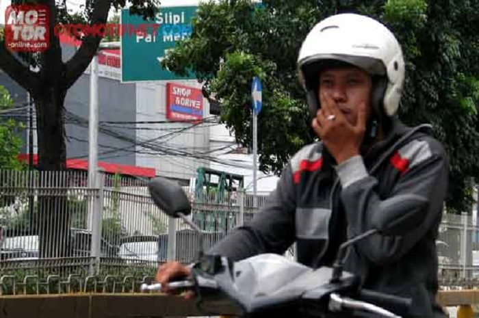 Ilustrasi naik motor sambil merokok.