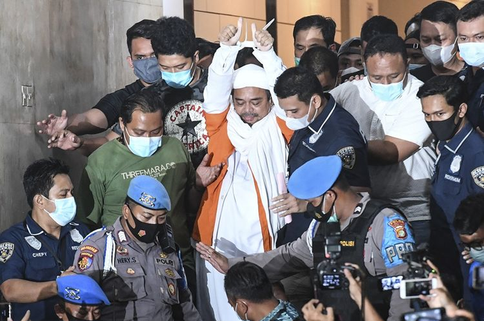 Imam Besar Front Pembela Islam (FPI) Habib Rizieq Shihab (tengah) berjalan menuju mobil tahanan usai diperiksa di Mapolda Metro Jaya, Jakarta, Minggu (13/12/2020) dini hari. Rizieq Shihab ditahan penyidik Ditreskrimum Polda Metro Jaya untuk kepentingan penyidikan perkara kasus dugaan pelanggaran protokol kesehatan COVID-19.