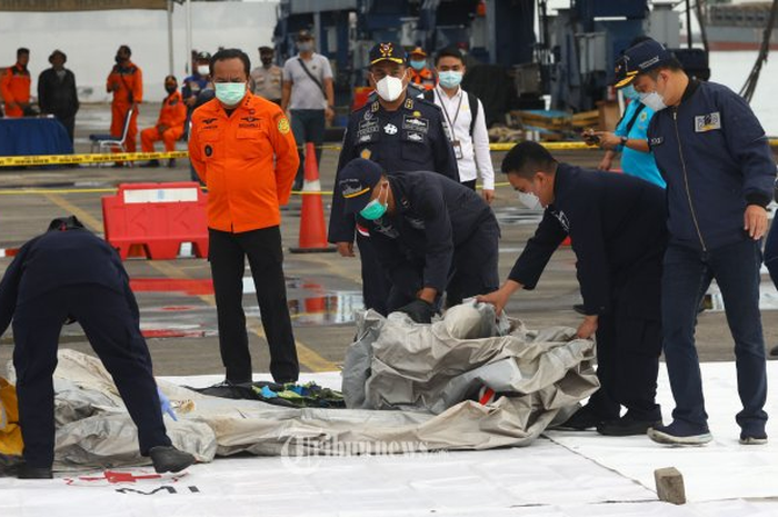 Petugas Basarnas memeriksa benda yang diduga serpihan dari pesawat Sriwijaya Air SJ 182 rute Jakarta - Pontianak yang hilang kontak di perairan Pulau Seribu, di Dermaga JICT, Jakarta, Minggu (10/1/2021). Pesawat Sriwijaya Air SJ 182 yang hilang kontak pada Sabtu (9/1) sekitar pukul 14.40 WIB di keti
