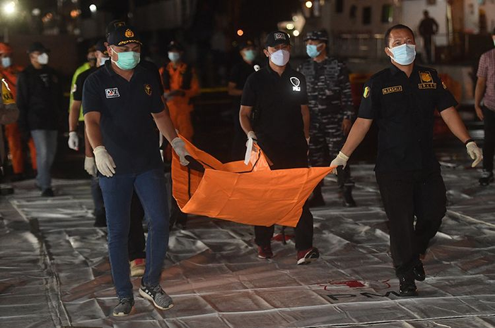 Petugas DVI Polri membawa kantong jenazah yang diduga berisi potongan tubuh korban pesawat Sriwijaya Air SJ 182 rute Jakarta - Pontianak yang hilang kontak di perairan Pulau Seribu, di Dermaga JICT, Jakarta, Minggu (10/1/2021). 