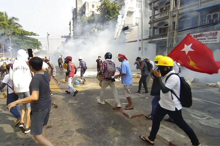 Pengunjuk rasa anti-kudeta bereaksi ketika asap dari gas air mata naik di Yangon, Myanmar Minggu (28/2/2021)