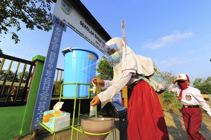 Seorang siswi mencuci tangannya sebelum memasuki gerbang sekolah saat hari pertama dimulainya kembali pembelajaran tatap muka di SDN 212/IV, Kota Jambi, Jambi, Senin (1/3/2021). 