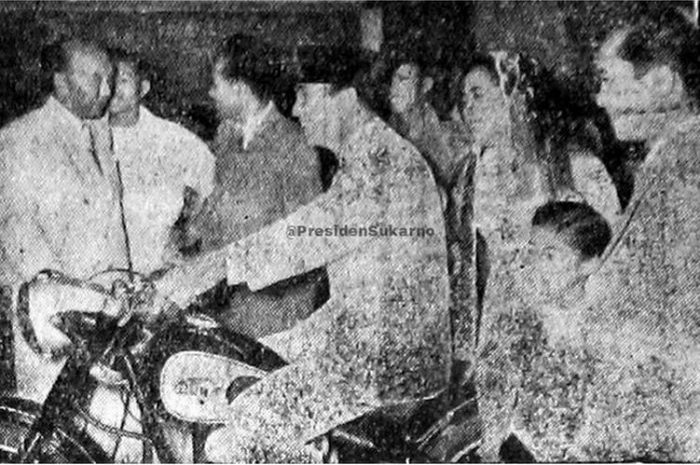 Foto Presiden Soekarno duduk di atas sebuah motor klasik.