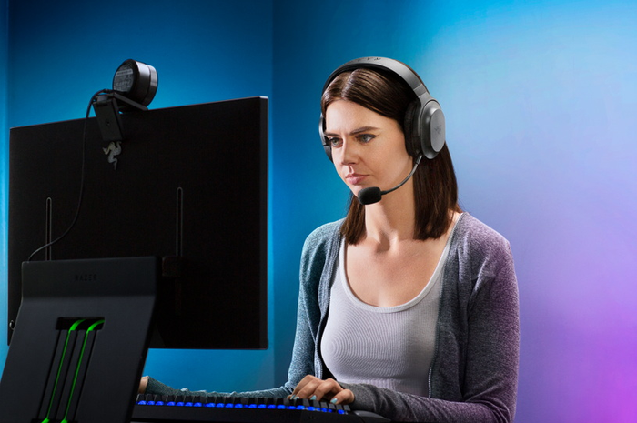 Ilustrasi seorang wanita menggunakan headset gaming Razer Barracuda X untuk bermain game PC