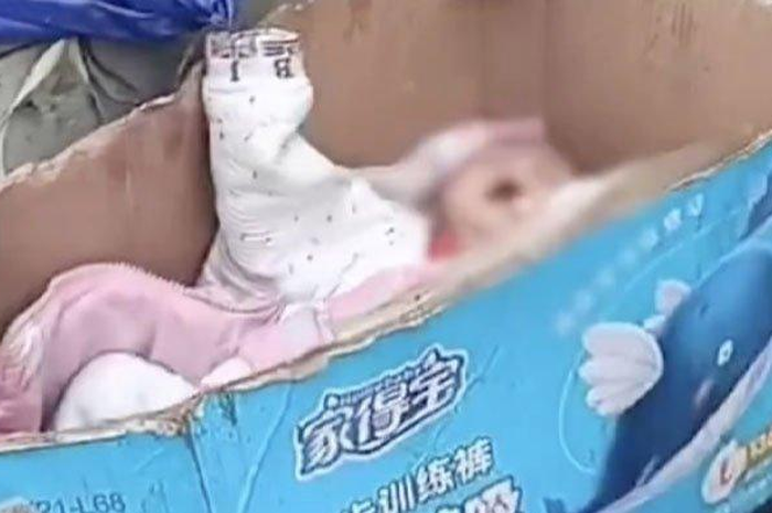 Sebuah video viral menunjukkan seorang bayi berada di dalam kotak kertas bekas di sebelah ember yang digunakan untuk pigswill 