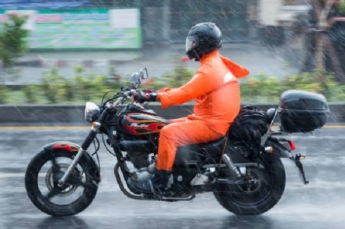 Ilustrasi berkendara pakai jas hujan. Ini jas hujan yang aman untuk pemotor.