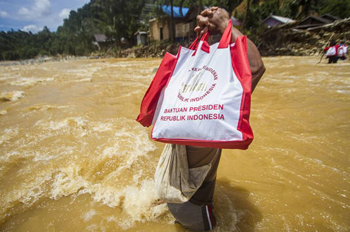 Seorang warga menyeberangi sungai saat memikul paket sembako bantuan Presiden di pedalaman Pegunungan Meratus, Desa Datar Ajab, Kalimantan Selatan. 