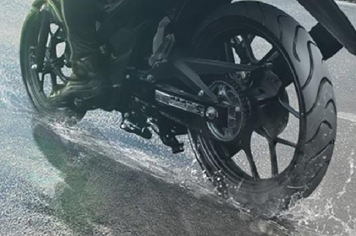 Ilustrasi ban motor melibas hujan. Apa benar kurangi tekanan angin ban saat hujan lebih aman buat pemotor? Simak penjelasannya.