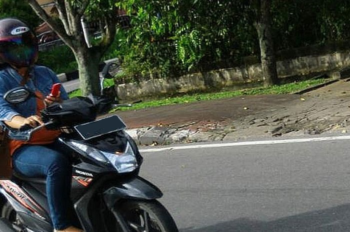 Foto ilustrasi. Masih berani naik motor sambil main HP terutama saat Operasi Zebra 2022, jangan kaget kalau kena denda Rp 750 ribu.