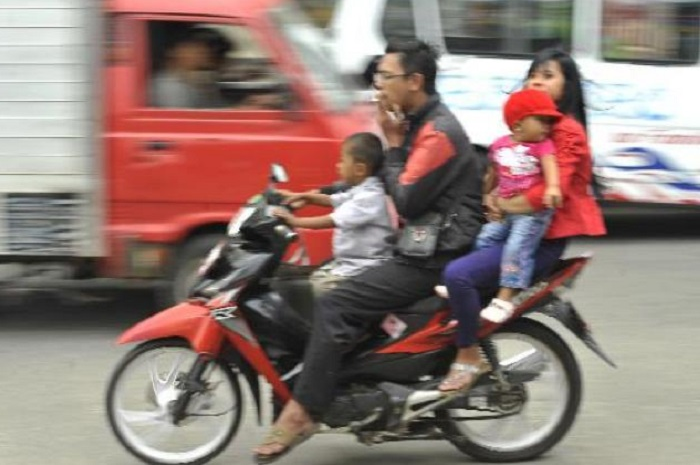 Ilustrasi pemotor tak pakai helm.