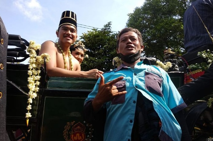 Tukang parkir di Solo bernama Mulyadi (kanan) berfoto bersama Kaesang Pangarep (kiri) saat kirab pernikahan Kaesang dan Erina melintasi jalan Slamet Riyadi Kota Solo, Minggu (11/12/2022).