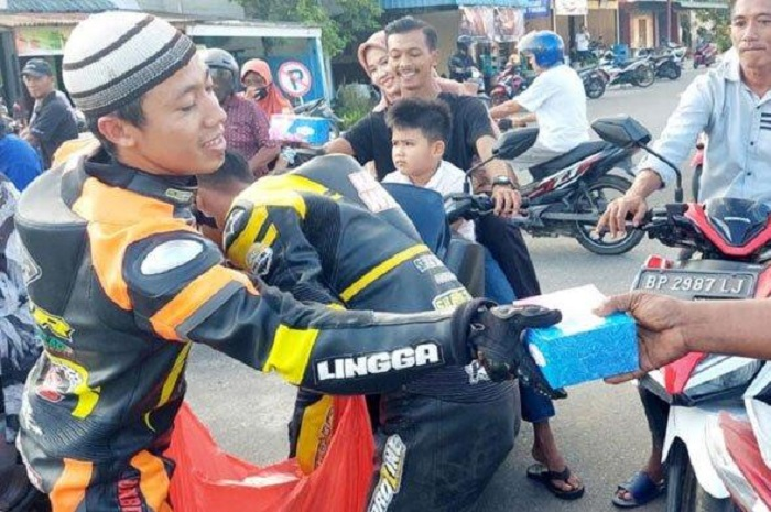 Pembalap motor berbagi takjil setelah latihan balap di jalan Implasemen Dabo Singkep, Kabupaten Lingga, Provinsi Kepulauan Riau, Minggu (26/3/2023).