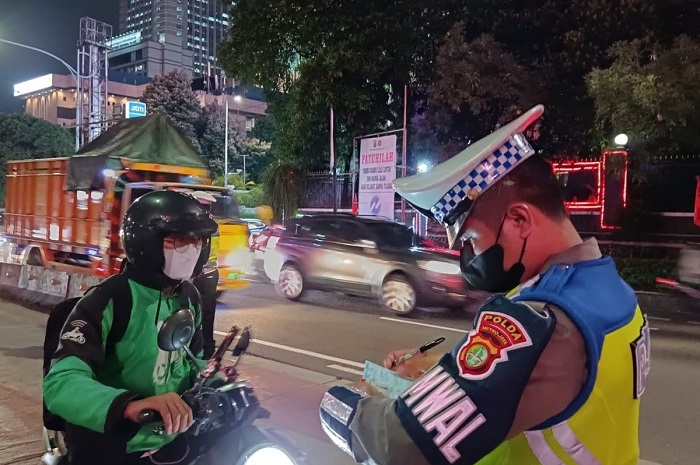 Ilustrasi polisi menindak tilang manual kepada pemotor.