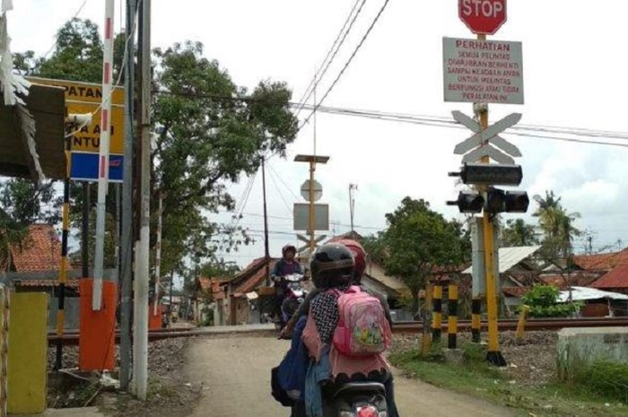 Ilustrasi motor nyebrang pintu perlintasan kereta api.