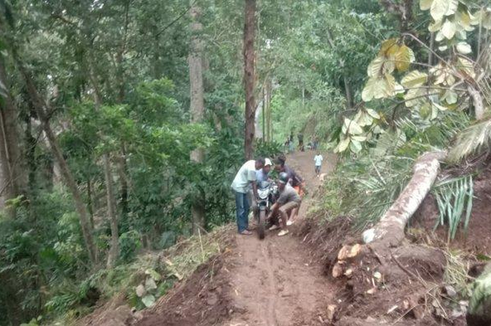 Jalan longsor bikin motor tidak bisa melintas. Warga bikin jasa gotong motor dengan tarif Rp 20 ribu