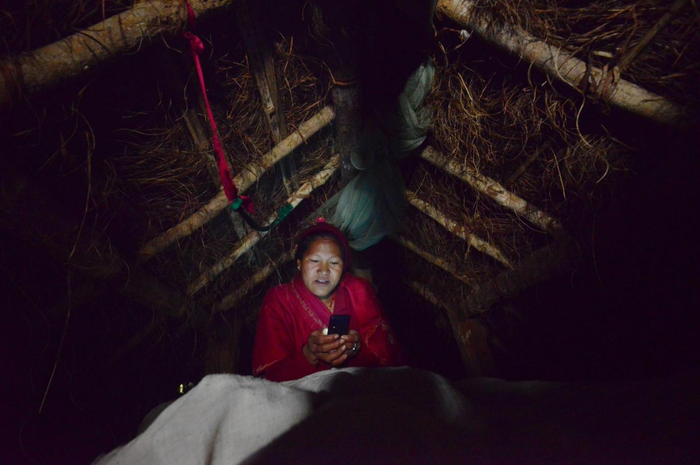 Wanita di Nepal duduk dengan api karena mereka tinggal di sebuah gubuk Chhaupadi selama masa menstruasi.
