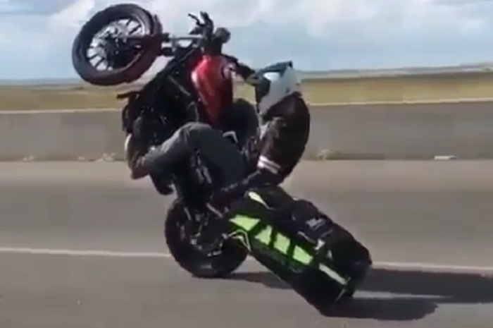 Seorang freestyler pamer aksi wheelie sambil megang koper di tangan kirinya