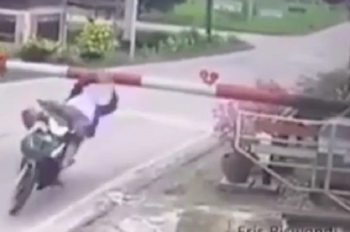 Emak-emak tersangkut di palang lintasan kereta api, karena naik motor enggak fokus.