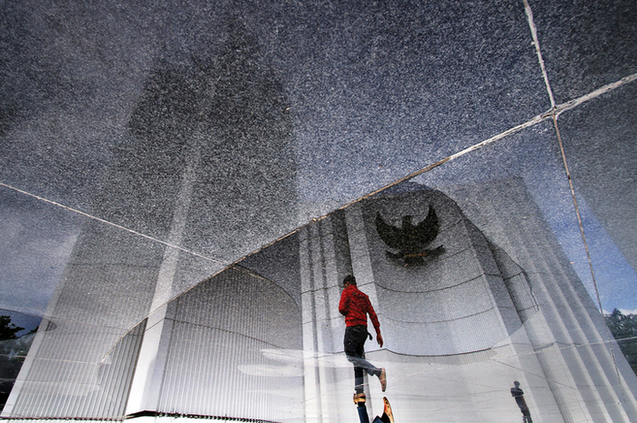 Refleksi seorang pengunjung yang melintas di pelataran Monumen Juang Pancasila, Bandung. Dalam perin