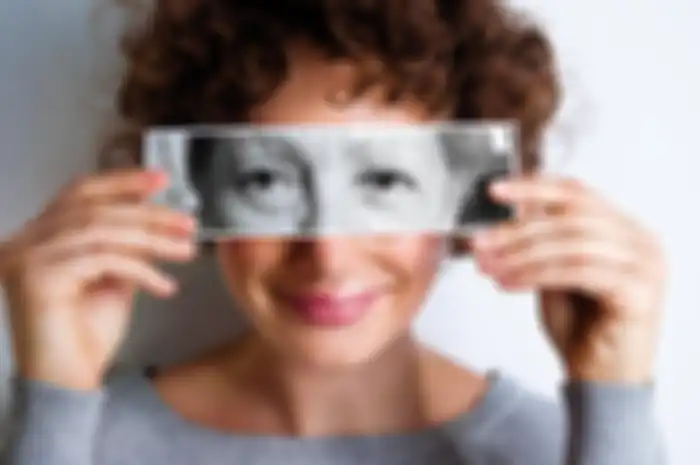 Woman with photo of elderly woman's eyes on hers'