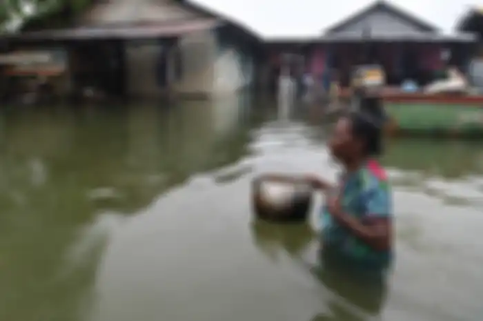 Seorang warga menerobos banjir yang melanda permukiman mereka di dekat Danau Sentani, Sentani, Jayapura, Papua, Selasa (19/3/2019). Akibat banjir bandang yang melanda Sentani sejak Sabtu (16/3) lalu, jumlah warga yang mengungsi ke sejumlah posko pengungsian bertambah menjadi sedikitnya enam ribu ora