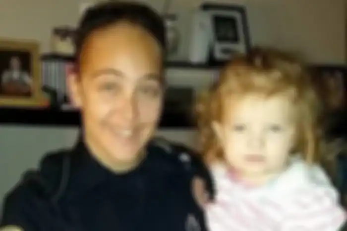 Cassie Baker (29) saat masih berseragam polwan tengah menggendong mendiang putrinya.