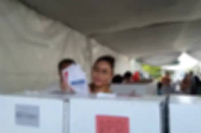 Inul Daratista memasukkan surat suaranya ke dalam kotak suara yang tersegel