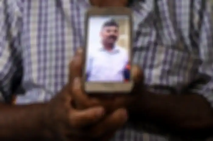 Sang ayah, Velusami Raju, saat memegang foto anaknya, Ramesh Raju, yang tewas dan menjadi pahlawan di pengeboman gereja di Sri Lanka.