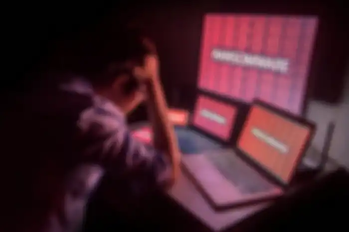 Young Asian male frustrated, confused and headache by ransomware attack on desktop screen, notebook and smartphone, cyber attack and internet security concepts