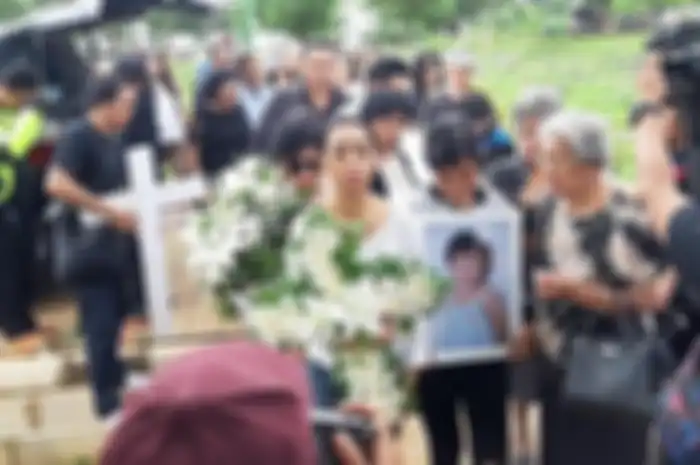 Karen Pooroe pegang foto anaknya di pemakaman
