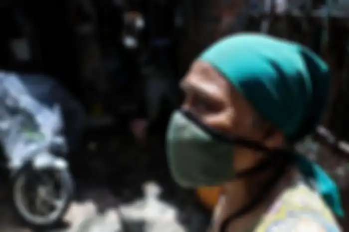 Seorang warga menggunakan masker berdiri didepan rumahnya di Jalan Tambora RT 01/07, Kelurahan Tambora, Jakarta Barat, Rabu (1/4/2020). Sejumlah kelurahan di Ibu Kota mulai menutup akses jalan untuk mencegah penyebaran virus corona atau COVID-19.