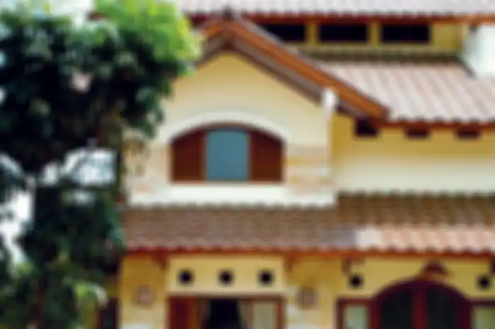 Tampak depan rumah memperlihatkan sistem atap bertingkat dengan bukaan-bukaan yang dapat membantu mengalirkan udara di dalam rumah.