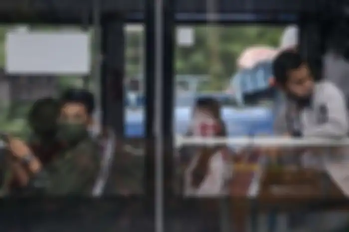Penumpang menggunakan masker saat naik Transjakart.