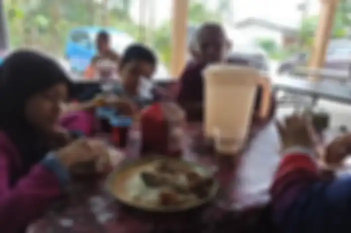 Keluarga Azam Mahat menikmati hidangan di salah satu rumah yang disangkanya warung di Kelantan, Malaysia, pada 2 Januari