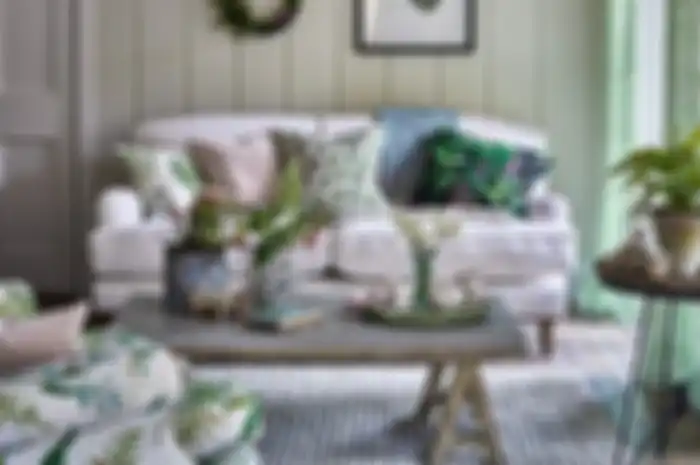 Ilustrasi bantal sofa motif flora dengan warna hijau menguatkan kesan segar dan alami.