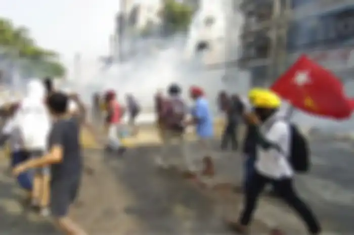 Pengunjuk rasa anti-kudeta bereaksi ketika asap dari gas air mata naik di Yangon, Myanmar Minggu (28/2/2021)